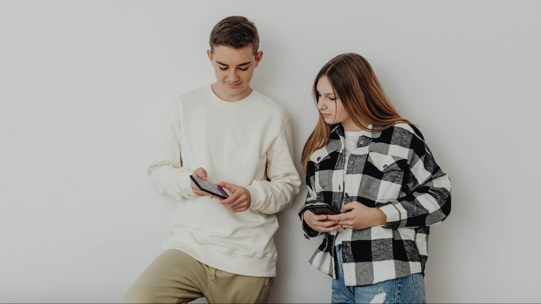 Two people both look at something on a cell phone