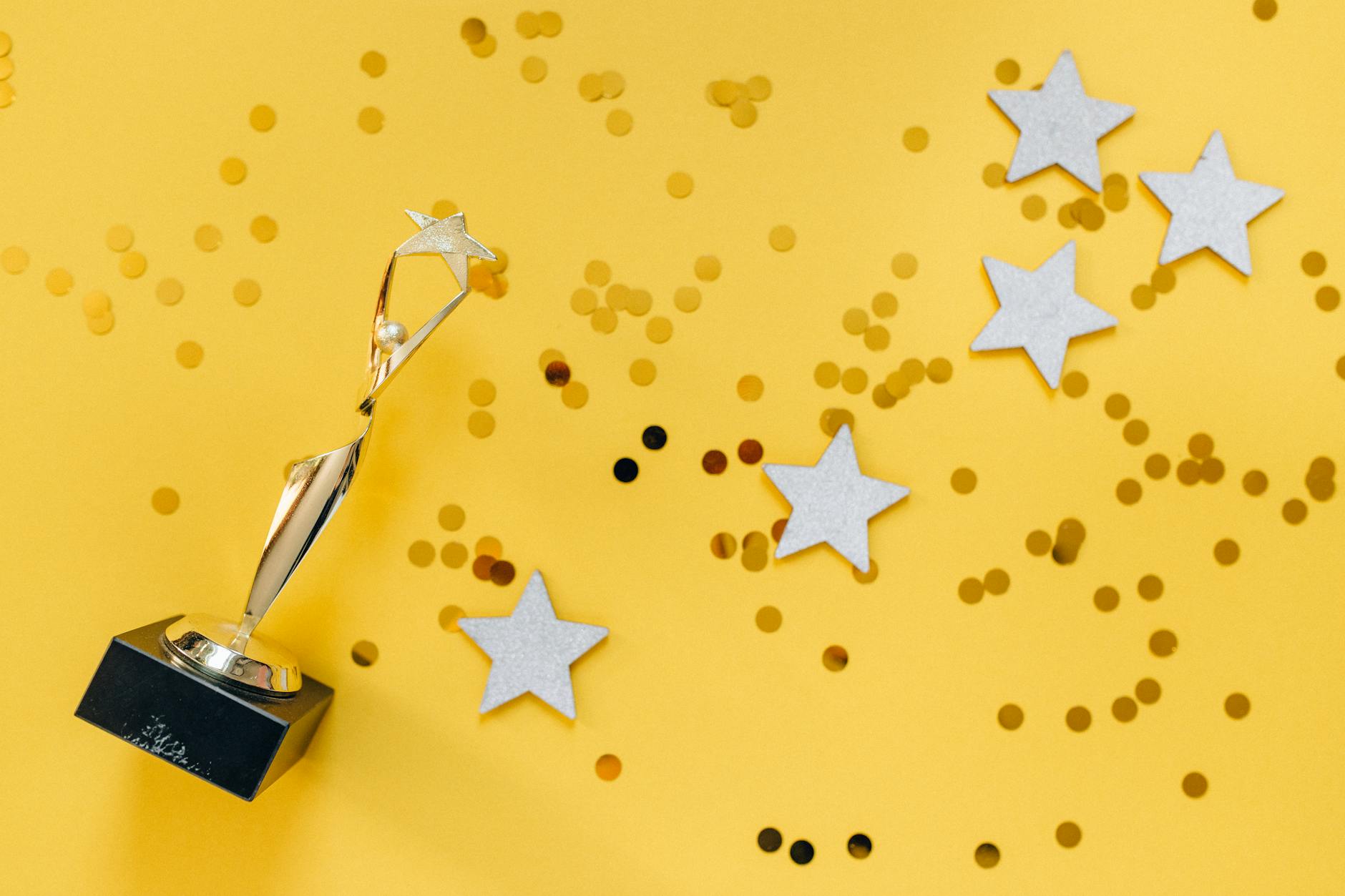 A trophy and confetti sitting on a yellow background