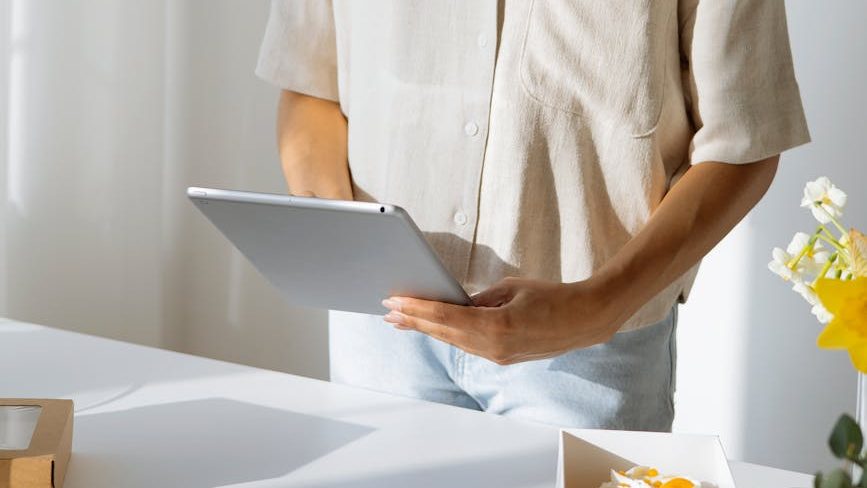 Someone scrolling through an iPad in front of yellow flowers