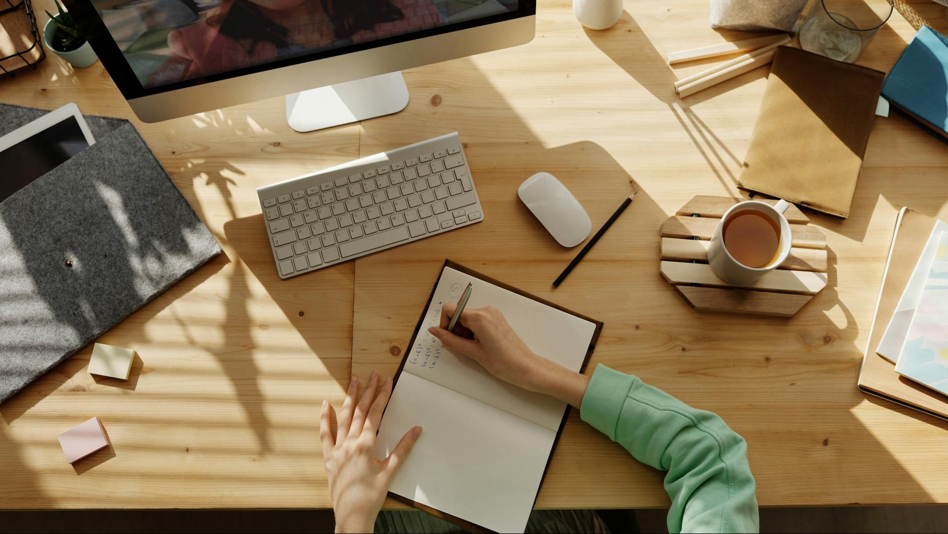 A photo of someone writing things down on paper while learning from a computer