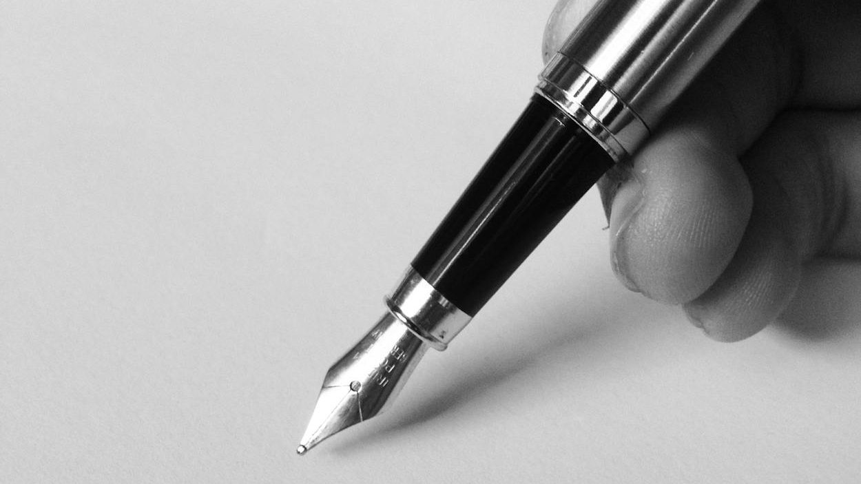 A black-and-white photo of a hand holding a pen