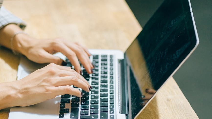 Hands typing on a laptop
